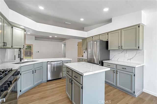 1534 Princeton Ave, Madera, CA 93637 - kitchen with appliances with stainless steel finishes, a peninsula, light wood-type flooring, decorative backsplash, and gray cabinets