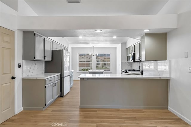 1534 Princeton Ave, Madera, CA 93637 - kitchen with gray cabinetry, tasteful backsplash, light wood-type flooring, a peninsula, and light countertops