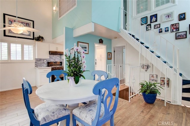 17072 5th St Unit A, Sunset Beach, CA 90742 - dining area featuring a towering ceiling, light wood finished floors, ceiling fan, and stairs