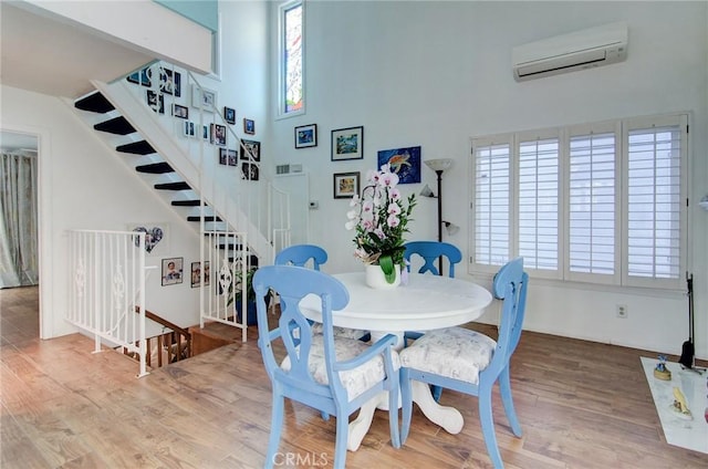 17072 5th St Unit A, Sunset Beach, CA 90742 - dining space featuring wood finished floors, a wall unit AC, stairs, and a towering ceiling