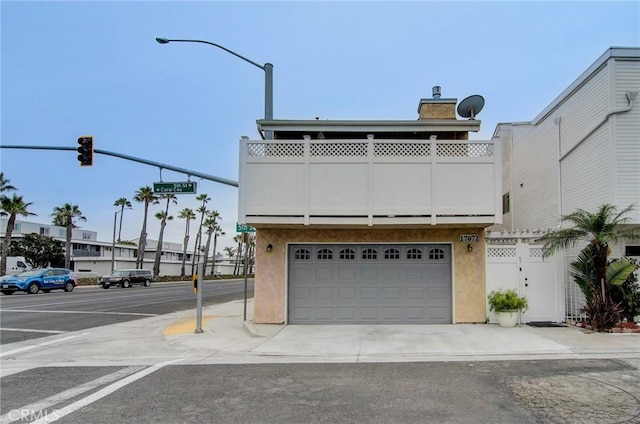 17072 5th St Unit A, Sunset Beach, CA 90742 - view of front of property with stucco siding, a chimney, a balcony, and an attached garage