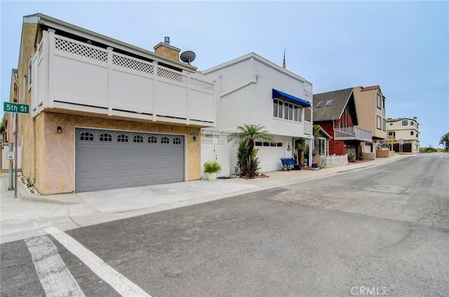 17072 5th St Unit A, Sunset Beach, CA 90742 - view of front of property featuring an attached garage, a chimney, driveway, and stucco siding