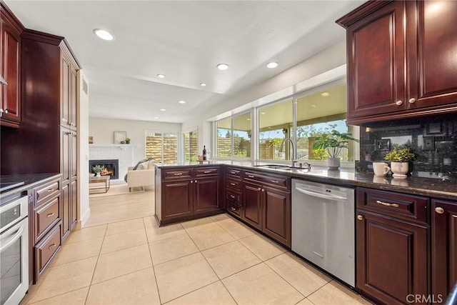 2260 Ardemore Dr, Fullerton, CA 92833 - kitchen with reddish brown cabinets, appliances with stainless steel finishes, a warm lit fireplace, light tile patterned floors, and recessed lighting