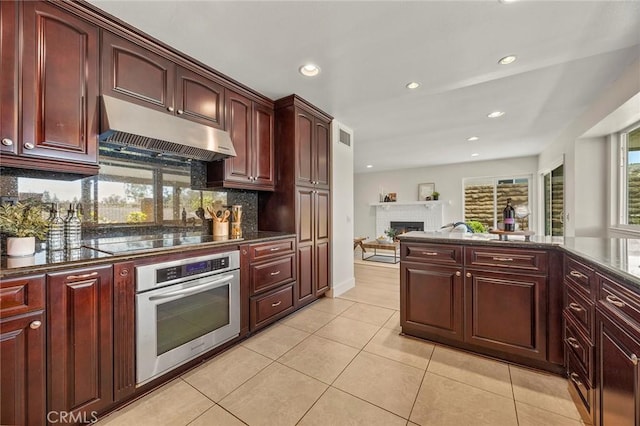 2260 Ardemore Dr, Fullerton, CA 92833 - kitchen with dark brown cabinets, stainless steel oven, under cabinet range hood, a brick fireplace, and recessed lighting