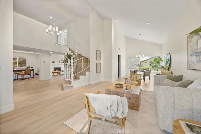 2260 Ardemore Dr, Fullerton, CA 92833 - living room featuring a chandelier, high vaulted ceiling, stairs, wood finished floors, and a warm lit fireplace