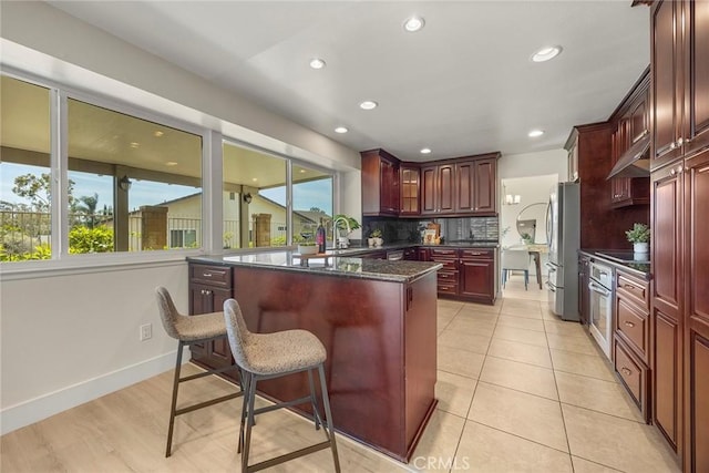 2260 Ardemore Dr, Fullerton, CA 92833 - kitchen with reddish brown cabinets, backsplash, stainless steel appliances, a breakfast bar, and recessed lighting
