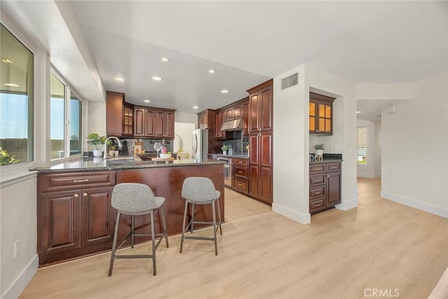 2260 Ardemore Dr, Fullerton, CA 92833 - kitchen featuring a peninsula, recessed lighting, a breakfast bar area, glass insert cabinets, and light wood-type flooring