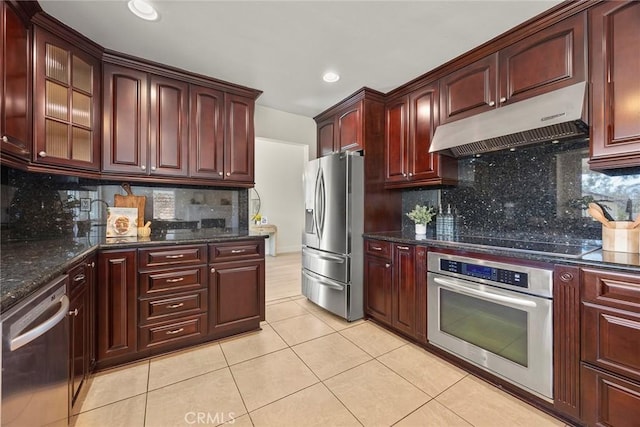 2260 Ardemore Dr, Fullerton, CA 92833 - kitchen with stainless steel appliances, under cabinet range hood, light tile patterned flooring, reddish brown cabinets, and tasteful backsplash