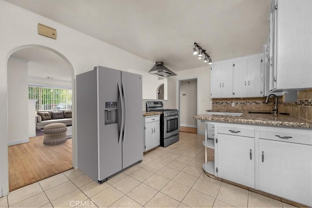 404 W Robinson Ave, Fresno, CA 93705 - kitchen with arched walkways, stainless steel appliances, white cabinetry, light tile patterned flooring, and decorative backsplash
