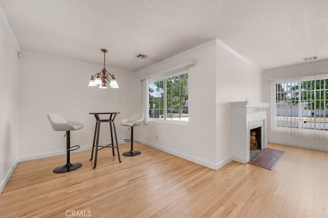 404 W Robinson Ave, Fresno, CA 93705 - unfurnished dining area featuring wood finished floors, crown molding, plenty of natural light, a fireplace with flush hearth, and a chandelier