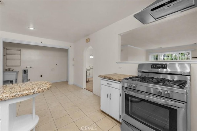 404 W Robinson Ave, Fresno, CA 93705 - kitchen featuring stainless steel gas stove, extractor fan, arched walkways, white cabinetry, and light tile patterned floors
