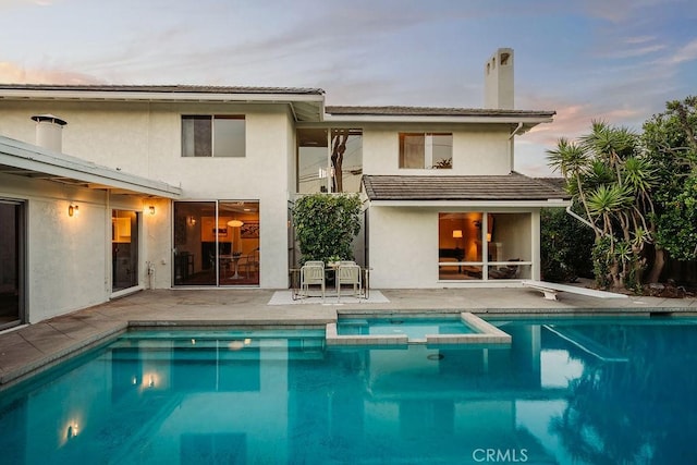 2443 Windward Ln, Newport Beach, CA 92660 - rear view of house with a patio, a pool with connected hot tub, a chimney, and stucco siding