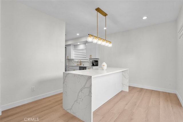 18340 Keswick St Unit 5, Reseda, CA 91335 - kitchen featuring light wood-type flooring, a peninsula, light stone countertops, recessed lighting, and hanging light fixtures