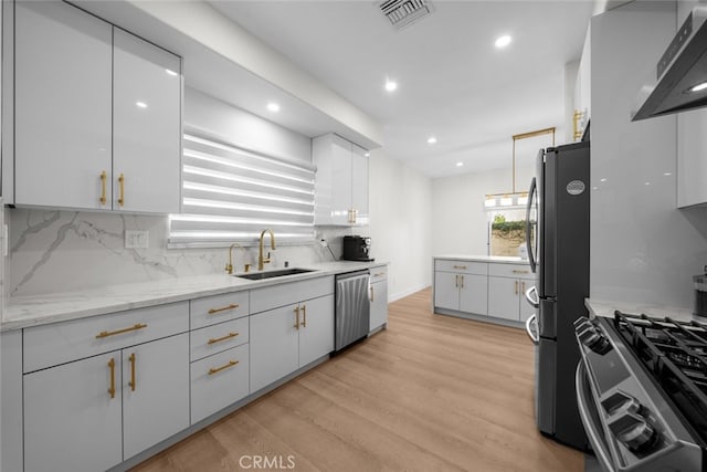 18340 Keswick St Unit 5, Reseda, CA 91335 - kitchen with white cabinets, wall chimney exhaust hood, light wood-style floors, appliances with stainless steel finishes, and recessed lighting