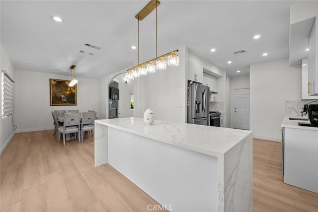 18340 Keswick St Unit 5, Reseda, CA 91335 - kitchen with arched walkways, white cabinets, light wood-type flooring, appliances with stainless steel finishes, and light stone countertops