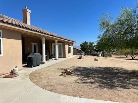 17134 Joshua Rd, Apple Valley, CA 92307 - rear view of house with stucco siding, a chimney, a tile roof, and a patio