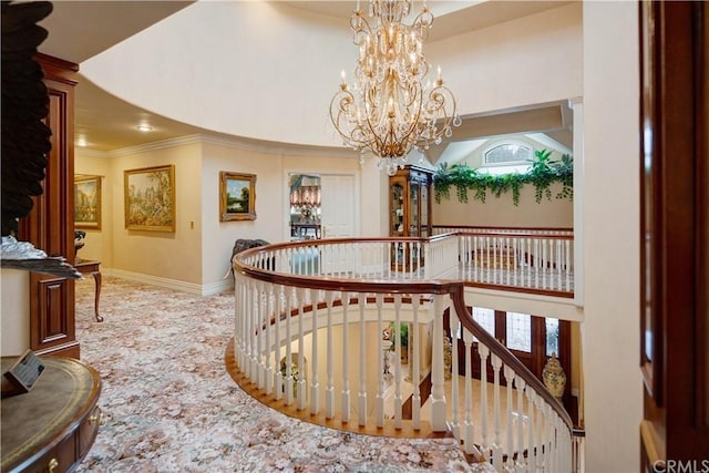 corridor featuring plenty of natural light, an inviting chandelier, crown molding, and a towering ceiling