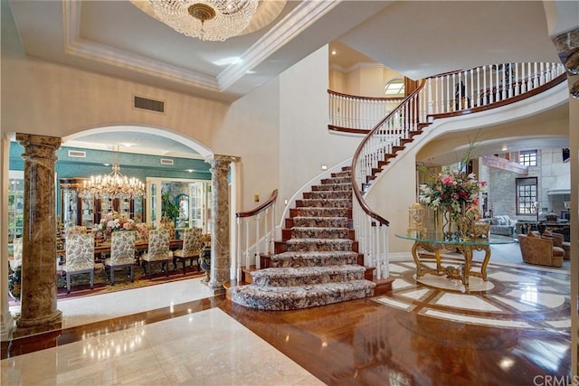 foyer with an inviting chandelier, tile floors, decorative columns, and a high ceiling