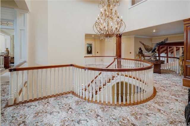 corridor featuring crown molding, an inviting chandelier, and a high ceiling