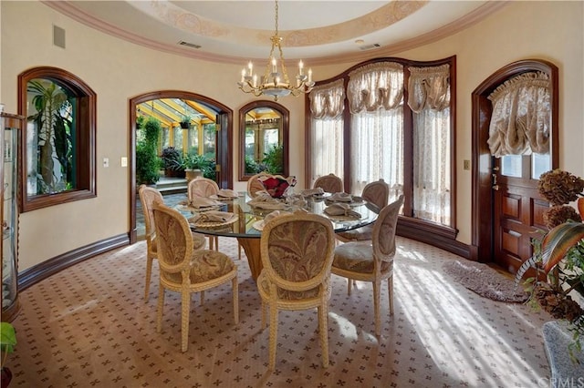 dining space with a notable chandelier, a raised ceiling, and ornamental molding