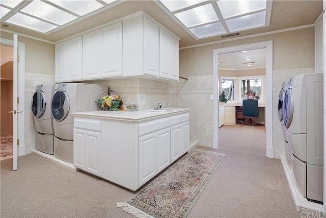 laundry area featuring light colored carpet, ornamental molding, washing machine and dryer, and tile walls