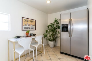 interior space featuring stainless steel refrigerator with ice dispenser and light tile patterned flooring