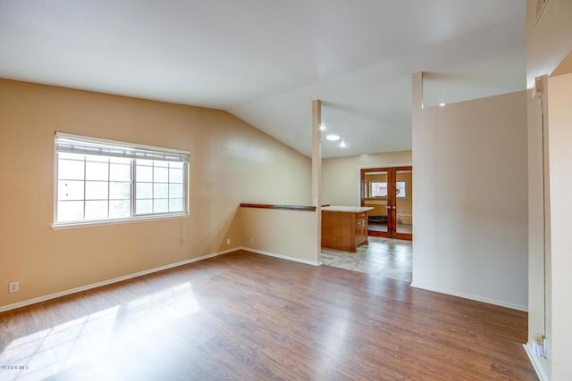 empty room with french doors, wood-type flooring, and vaulted ceiling