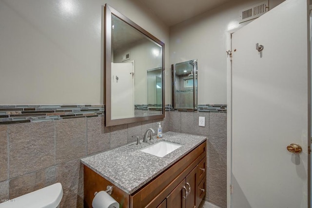 bathroom featuring tile walls, toilet, tasteful backsplash, and vanity