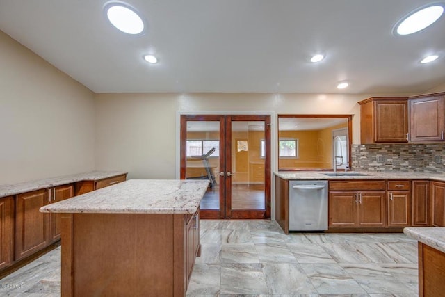 kitchen featuring decorative backsplash, light stone countertops, light tile patterned flooring, stainless steel dishwasher, and a kitchen island