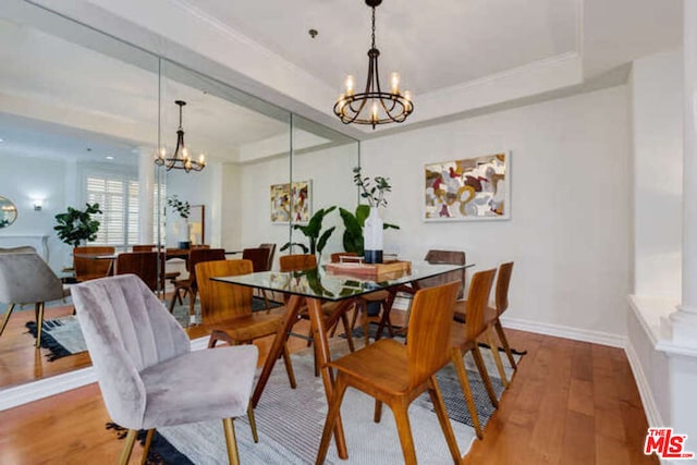 dining room with wood-type flooring, a chandelier, and a tray ceiling