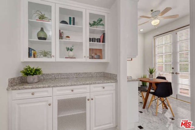 bar featuring ceiling fan, white cabinets, light stone countertops, and light tile patterned floors