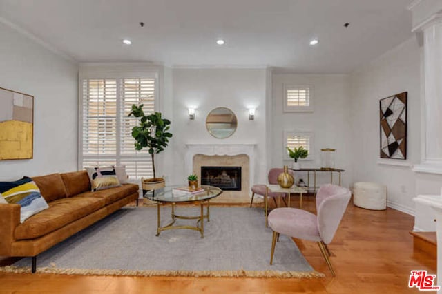 living room featuring a premium fireplace, light hardwood / wood-style floors, and crown molding