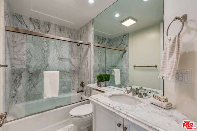 full bathroom featuring enclosed tub / shower combo, vanity, and toilet