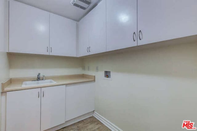 washroom with cabinets, hookup for a washing machine, sink, and light hardwood / wood-style floors