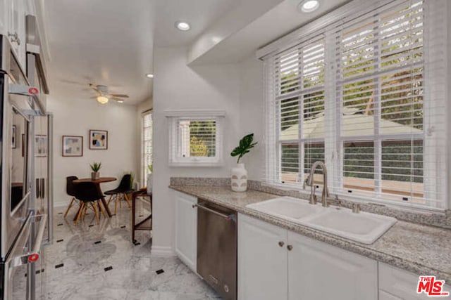 kitchen featuring light tile patterned floors, ceiling fan, sink, white cabinetry, and stainless steel dishwasher