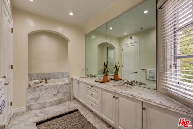 bathroom featuring double sink vanity, tile patterned flooring, and tiled bath