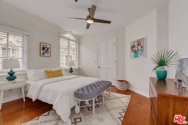 bedroom featuring ceiling fan, light wood-type flooring, and multiple windows