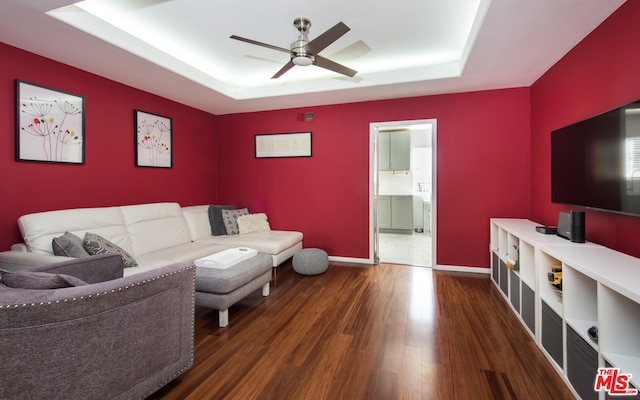 living room featuring ceiling fan, a raised ceiling, and dark tile patterned floors