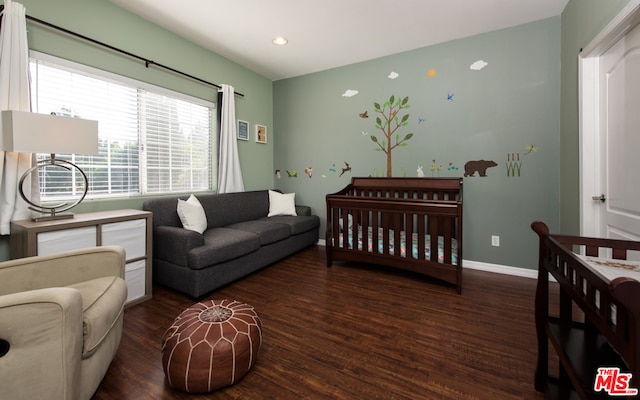 bedroom with a nursery area and dark hardwood / wood-style flooring