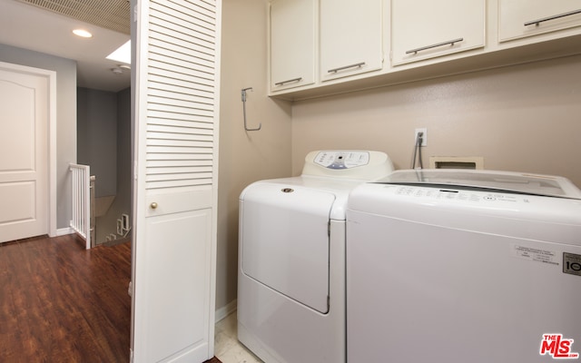 washroom with cabinets, wood-type flooring, and washer and clothes dryer