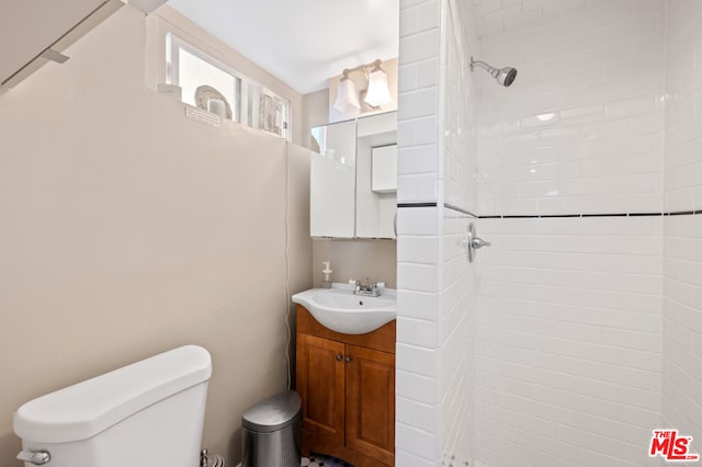 bathroom with vanity, a tile shower, and toilet