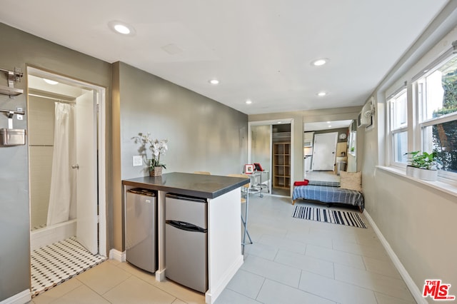 kitchen with kitchen peninsula, stainless steel refrigerator, light tile flooring, and fridge