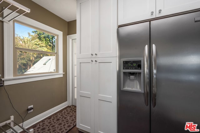 kitchen with stainless steel fridge, dark tile floors, and white cabinetry