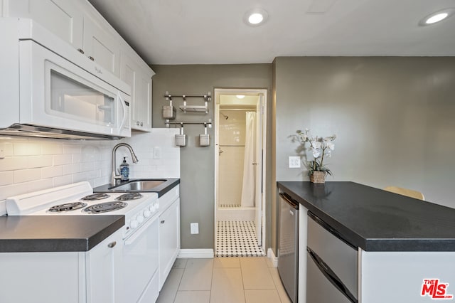 kitchen featuring light tile floors, tasteful backsplash, white appliances, white cabinetry, and sink