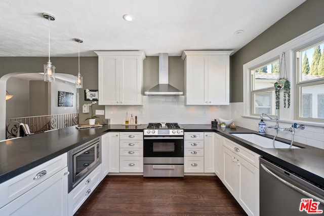 kitchen featuring sink, backsplash, stainless steel appliances, dark wood-type flooring, and wall chimney range hood