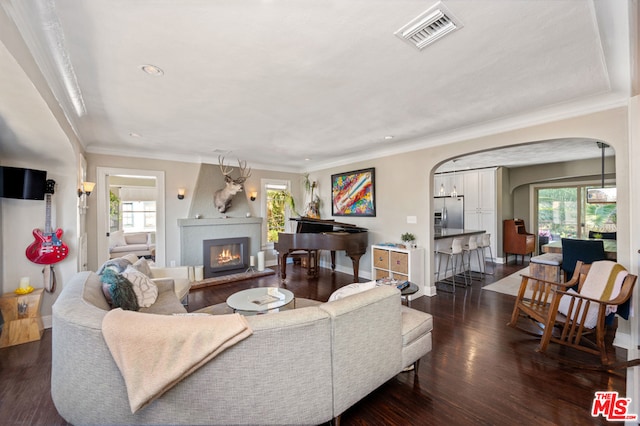 living room with plenty of natural light, dark wood-type flooring, and ornamental molding