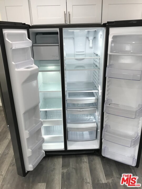 details with white cabinets, fridge, and dark wood-type flooring