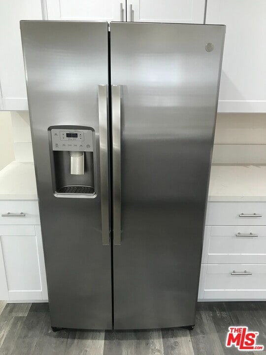 interior details with stainless steel fridge, dark hardwood / wood-style flooring, and white cabinetry