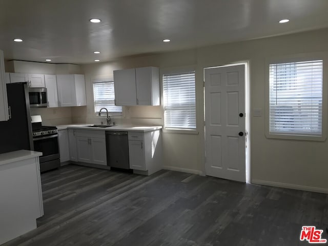 kitchen with appliances with stainless steel finishes, sink, dark hardwood / wood-style floors, and white cabinets