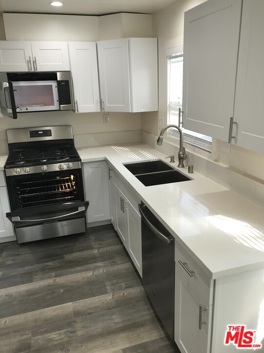 kitchen featuring dark hardwood / wood-style flooring, stainless steel appliances, white cabinetry, and sink